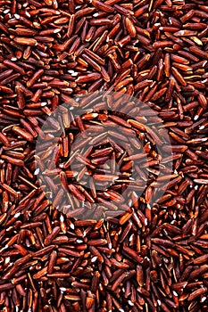 Wild raw red rice groats, food background texture, top view