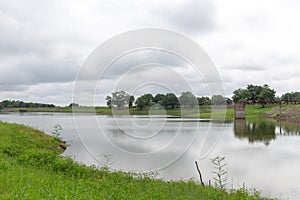 Wild river and green grass in summer cloudy landscape.