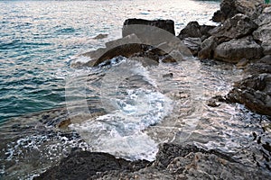 Wild sea panorama surrounded with sharp rock stones in summer on sunny sunset day. Beauty and force of deep water. Danger o