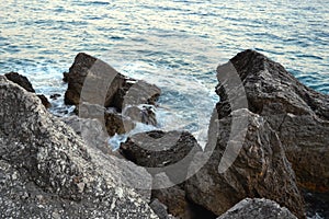 Wild sea panorama surrounded with sharp rock stones in summer on sunny sunset day. Beauty and force of deep water photo