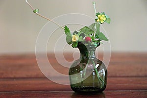 Wild strawberry bouquet in green glass vase