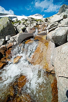 Wild stream infront of mountains and blue sky