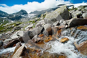 Wild stream infront of mountains and blue sky