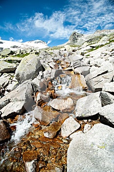 Wild stream infront of mountains and  blue sky
