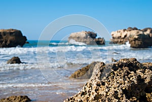 Wild summer ocean beach, Portugal. Clear sky, Rocks on sand