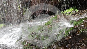 Wild and untamed waterfall in a remote wilderness area, water stream falls from above from a rock onto stones