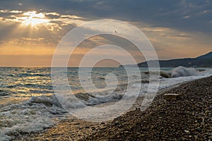 Wild waves on a pebble beach during a beautiful sunset