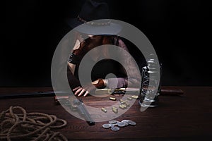 wild west girl with revolver gun sitting at the table with ammunition and silver coins