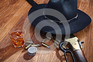 Wild west rifle and ammunitions with glass of whisky and ice with old silver dollar on wooden table