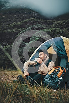 In the wilderness, my soul strums to the rhythm of bliss. a young man drinking coffee while camping in the wilderness.