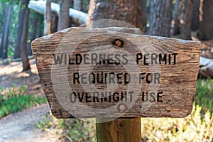 Wilderness permit required for overnight use sign on the wooden post in the national forest