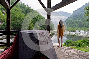 Wilderness solo traveler woman camping at the forest watching with orange sweater the woodland