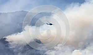 Wildfire Service Helicopter flying over BC Forest Fire and Smoke on the mountain near Hope