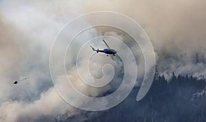 Wildfire Service Helicopter flying over BC Forest Fire and Smoke on the mountain near Hope