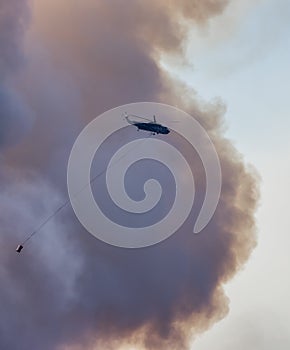 Wildfire Service Helicopter flying over BC Forest Fire and Smoke on the mountain near Hope