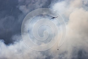 Wildfire Service Helicopter flying over BC Forest Fire and Smoke on the mountain near Hope