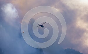 Wildfire Service Helicopter flying over BC Forest Fire and Smoke on the mountain near Hope