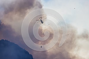 Wildfire Service Helicopter flying over BC Forest Fire and Smoke on the mountain near Hope