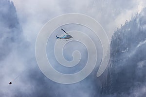 Wildfire Service Helicopter flying over BC Forest Fire and Smoke on the mountain near Hope