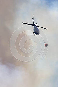 Wildfire Service Helicopter flying over BC Forest Fire and Smoke on the mountain near Hope