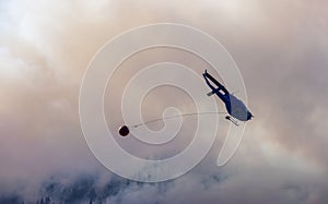 Wildfire Service Helicopter flying over BC Forest Fire and Smoke on the mountain near Hope