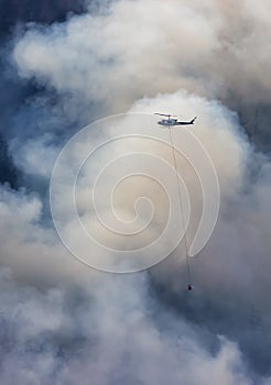 Wildfire Service Helicopter flying over BC Forest Fire and Smoke on the mountain near Hope