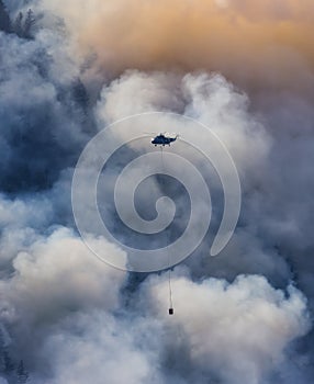 Wildfire Service Helicopter flying over BC Forest Fire and Smoke on the mountain near Hope