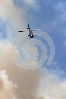 Wildfire Service Helicopter flying over BC Forest Fire and Smoke on the mountain near Hope