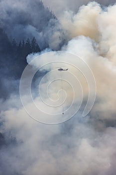 Wildfire Service Helicopter flying over BC Forest Fire and Smoke on the mountain near Hope