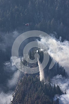 Wildfire Service Helicopter flying over BC Forest Fire and Smoke on the mountain near Hope