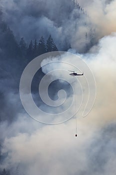 Wildfire Service Helicopter flying over BC Forest Fire and Smoke on the mountain near Hope