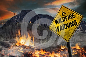 Wildfire warning sign against a forest fire background with burnt trees and vegetation