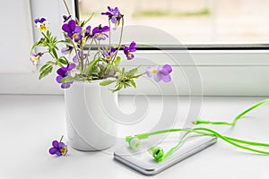 Wildflowers, phone and headphones on the windowsill