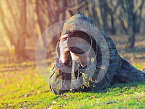 Wildlife, nature man photographer in camouflage outfit shooting, taking pictures