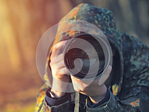 Wildlife, nature man photographer in camouflage outfit shooting, taking pictures