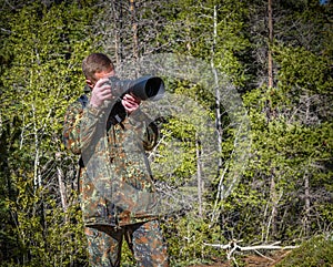 Wildlife, nature man photographer in camouflage outfit shooting, taking pictures