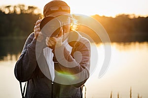 Wildlife photographer with camera photographing nature on lake at sunset