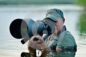 Wildlife photographer outdoor, standing in the water photo