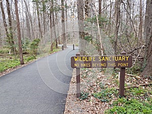 Wildlife sanctuary no bikes beyond this point sign and asphalt trail