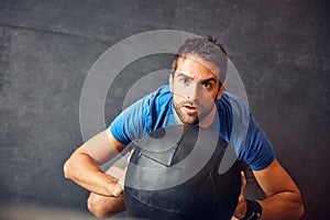 It will all pay off in the end. High angle shot of a handsome young man working out with a medicine ball in the gym.