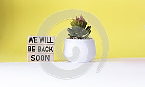 WE WILL BE BACK SOON text on wooden blocks and white and yellow background with cactus