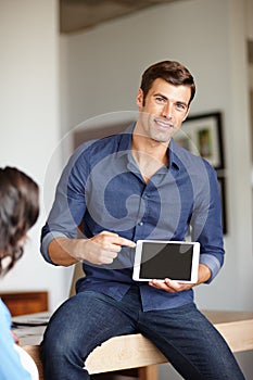 This will change your life. A handsome man pointing at his digital tablet while sitting at home with his wife.