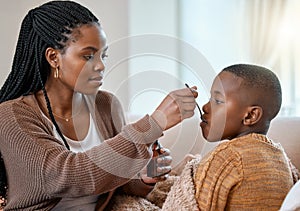 This will make you feel better. a young mother giving her sick son cough syrup at home.