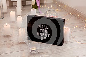 Will you marry me. The inscription on the card to a friend. Greeting for a wedding proposal with candles background