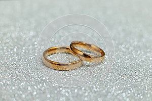 Will you marry me. Two golden wedding rings on silver glitter background. Engagement marriage proposal wedding