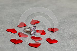 Will you marry me. Wedding ring many red hearts on concrete stone grey background. Engagement marriage proposal
