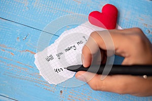 WILL YOU MARRY ME? word on paper note on blue wooden table background. Wedding, Romantic and Happy Valentineâ€™ s day holiday