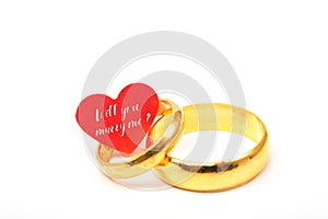 Will you marry me word on paper red hearts in wedding rings. Val