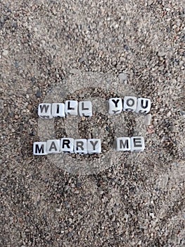 Will you marry me words written on sand at the beach