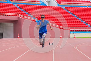 Willful Asian male athlete with prosthetics takes off speedily to surpass his running record on stadium track, motion blur depicts